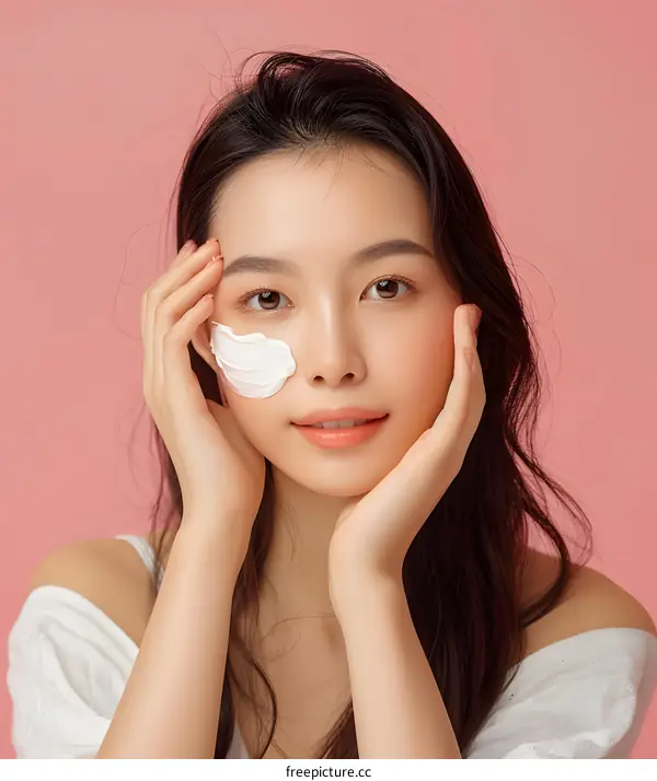 Asian Woman Applying Face Mask on Pink Background