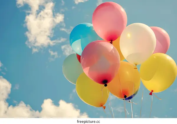 Colorful Balloons Floating in Blue Sky with White Clouds