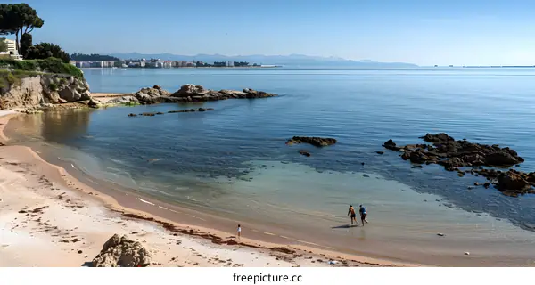 Scenic View of a Sandy Beach with Two People Walking on the Shore