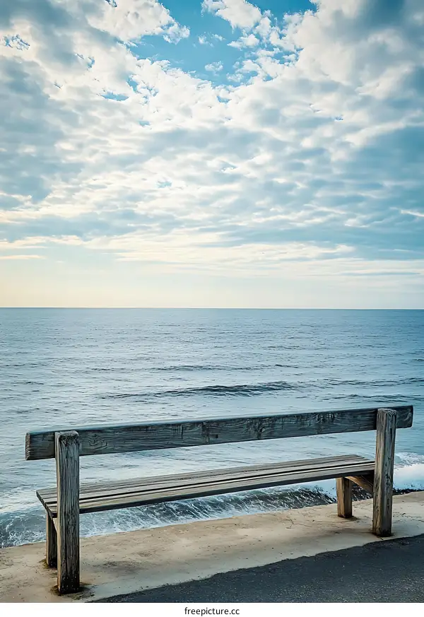 Wooden Bench Overlooking the Ocean with a Cloudy Sky