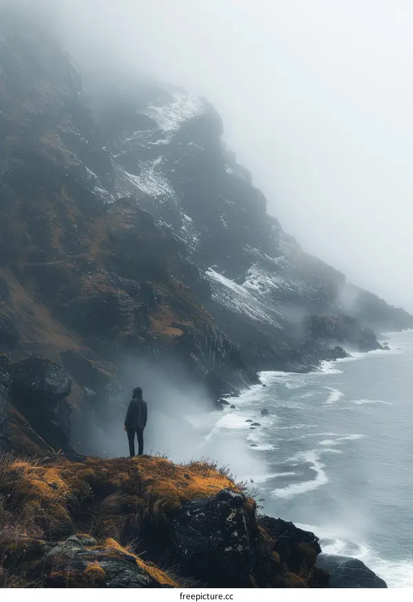 Man standing on a cliff overlooking the ocean