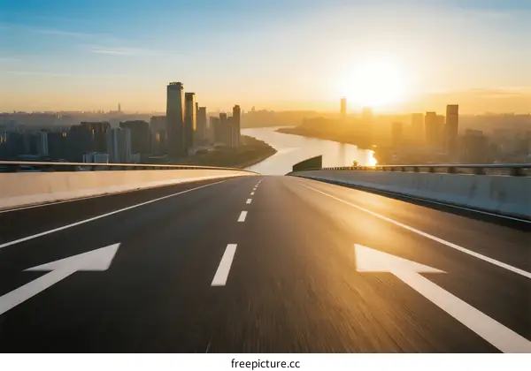 Sunset view of highway leading to urban skyline with river