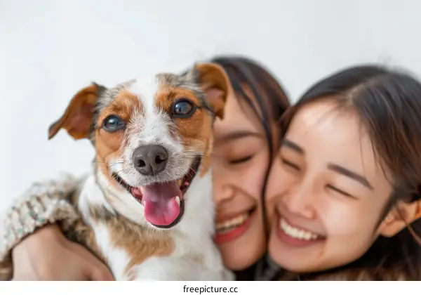 Two young Asian women hugging a small dog