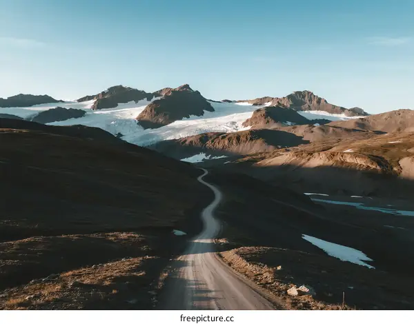 Scenic Mountain Road with Glaciers Under Clear Blue Sky