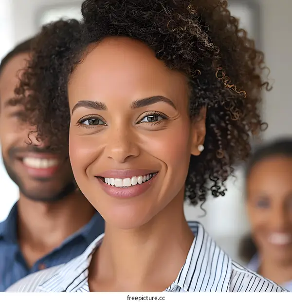 Smiling woman with curly hair and two other people in background