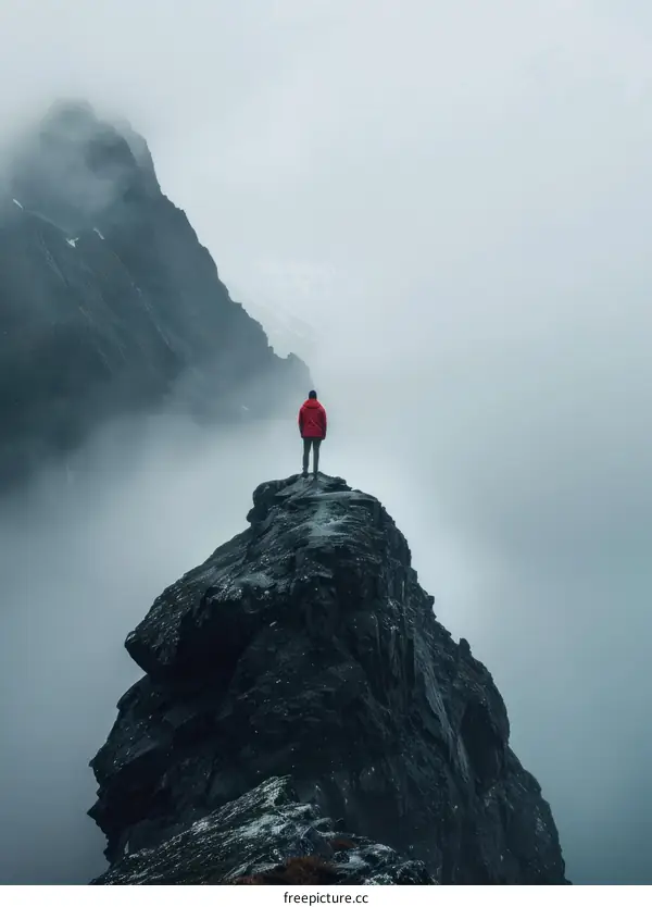 Man standing on a rock in the middle of a foggy mountain landscape