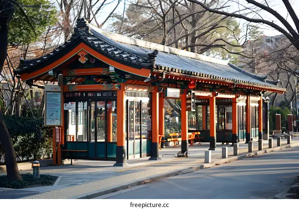 A traditional Japanese bus stop with a tiled roof and wooden pillars.