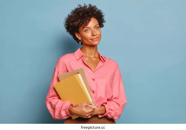 Woman Holding Books in Front of a Light Blue Background