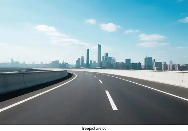 Smooth highway leading to modern city skyline under clear blue sky