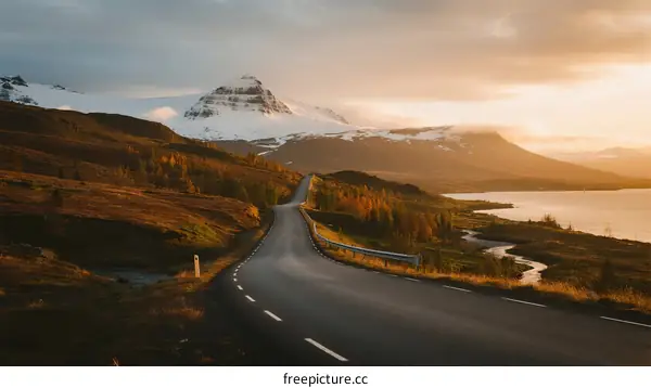 Scenic road winding through mountainous and lake landscape at sunset
