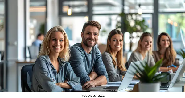 A group of people sitting in an office and smiling at the camera