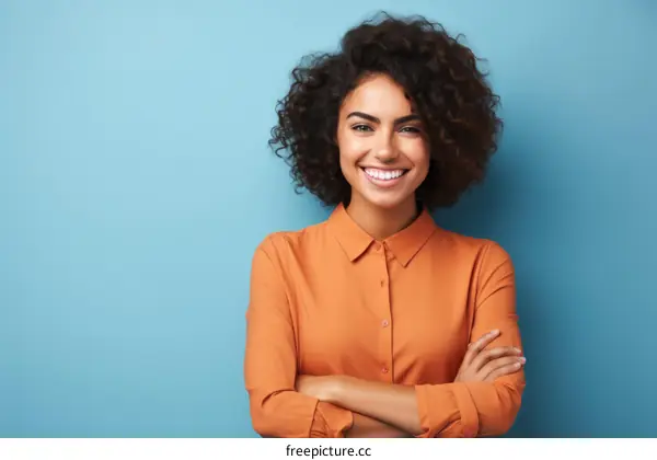 Portrait of a smiling young woman with curly hair wearing an orange shirt