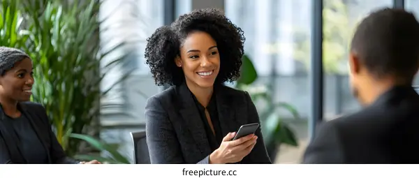 Smiling African American Woman Uses Her Phone in a Business Meeting