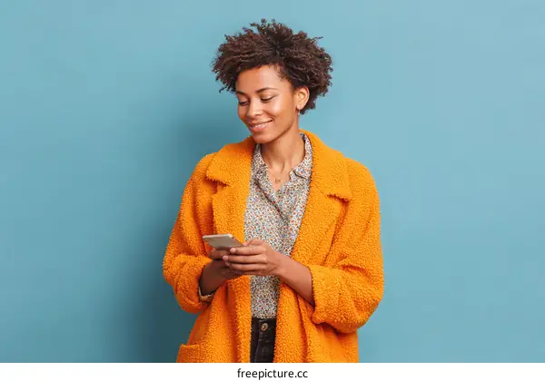 Young Woman Wearing Orange Coat Using Smartphone