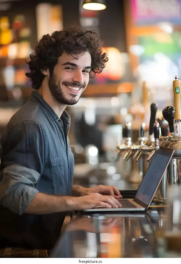 Smiling Man Using Laptop at Bar Counter