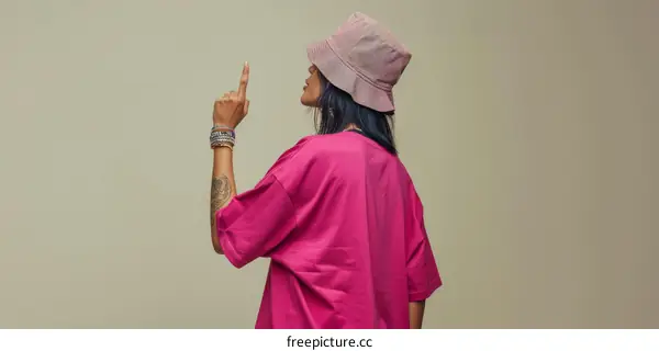 A woman in a pink bucket hat points her finger up