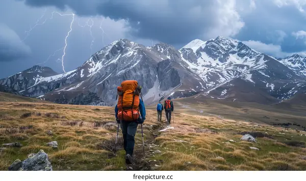 Three hikers walking in a mountain landscape with a lightning storm in the background