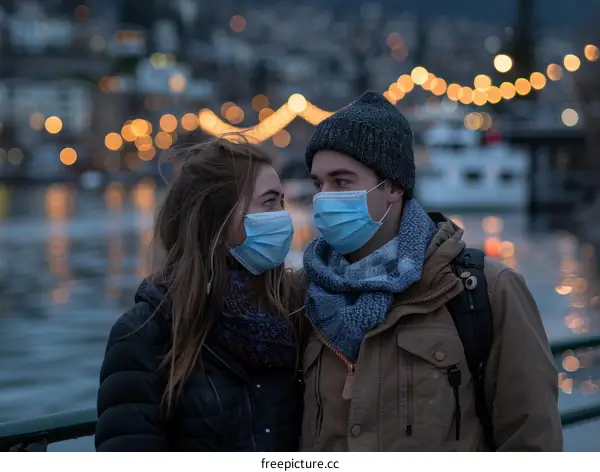 A masked couple gazes into each other's eyes in front of a blurred cityscape at dusk