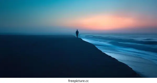 Man walking alone on beach at sunset