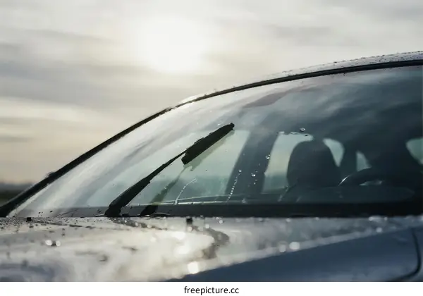 Car windshield wipers on rainy day with water droplets