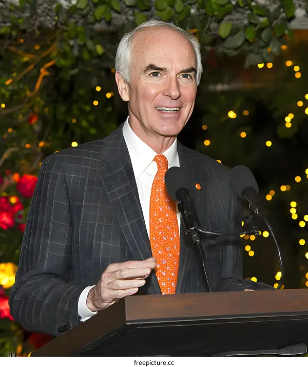Man in Suit Speaking at a Podium with Two Microphones