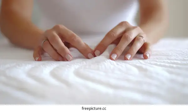 Closeup of Female Hands on a White Bed Sheet