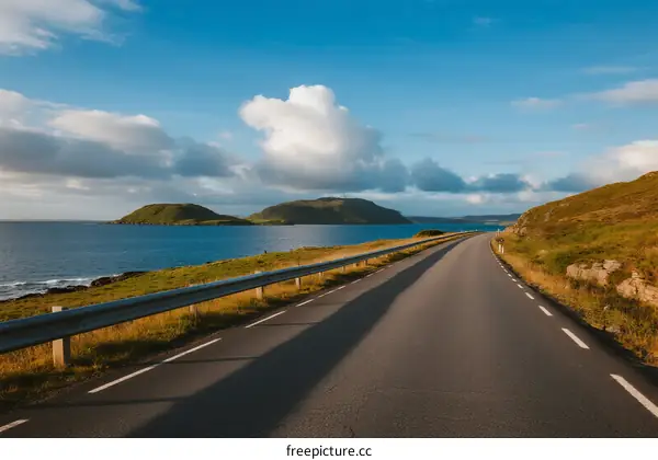 Scenic road along the coast with clear blue sky and clouds