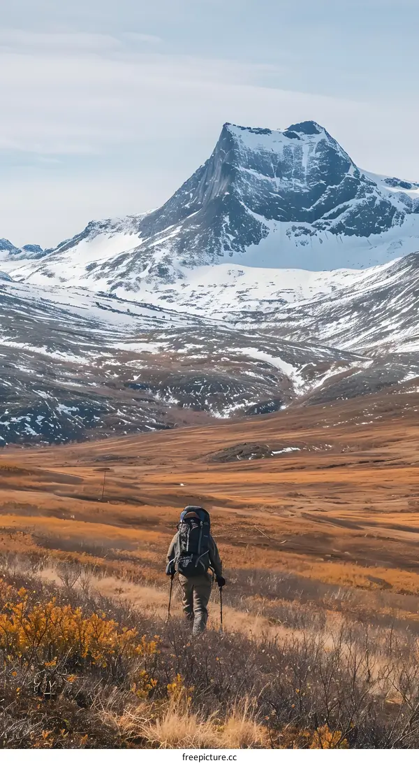 Backpacker Hiking Through Mountains with Snow Covered Peaks