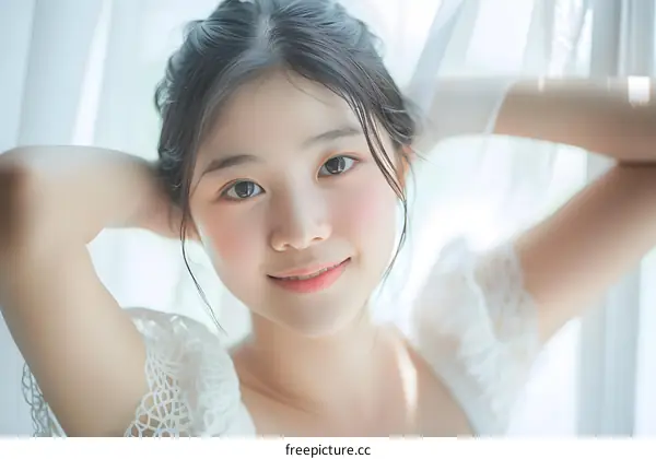 Portrait of a young Asian woman with long black hair and brown eyes smiling in front of a white background