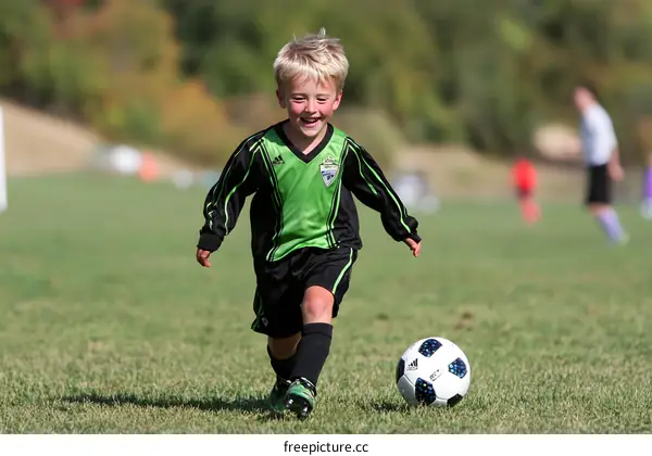 Young Boy Dribbling Soccer Ball on Field