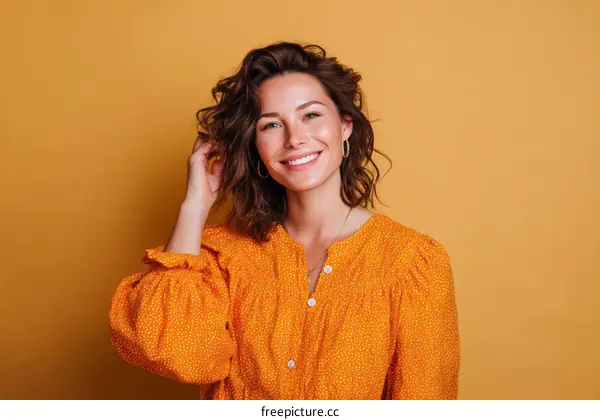 Smiling Woman in Orange Dotted Shirt Against a Mustard Background