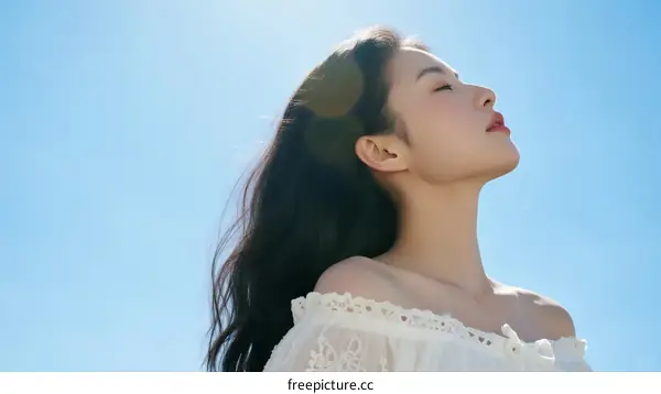 Young Woman Enjoying Warm Sunlight Under Clear Blue Sky