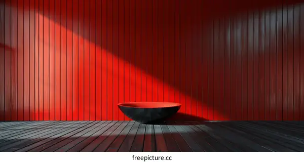 Black bowl on wooden floor with red wall