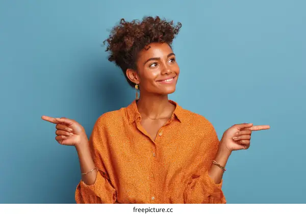 Happy Woman Pointing to the Right in an Orange Shirt