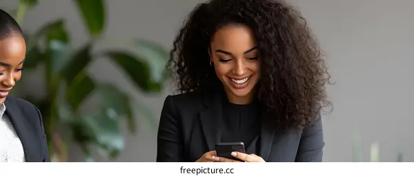 Smiling Black Woman Using Phone in Office