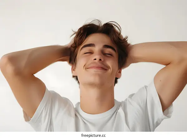 Portrait of a young man with his eyes closed and hands behind his head