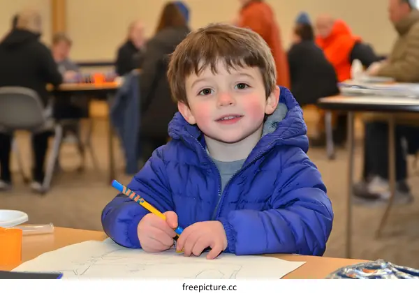 Young Boy in Blue Jacket Drawing at a Table