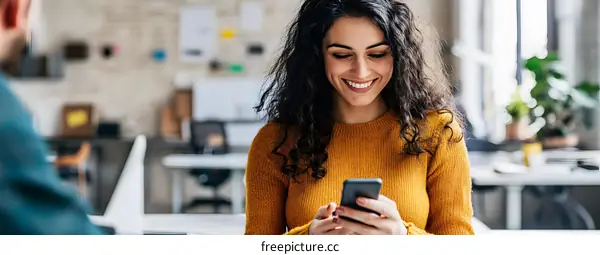 Smiling Woman Using Smartphone in Office