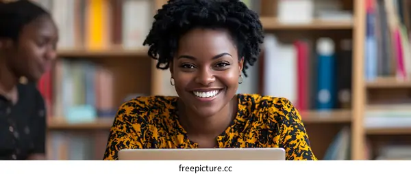 Smiling Black Woman Using Laptop in Library