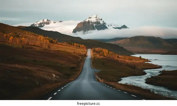 A scenic road leading through a picturesque mountainous area with snow-capped peaks