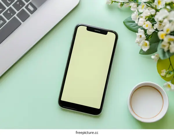 Modern Minimalist Flat Lay with Smartphone, Laptop, Flowers, and Coffee on Green Background
