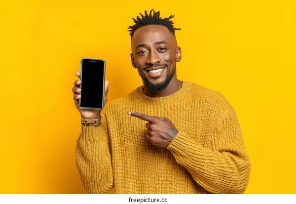 Smiling Man Showing Smartphone Against Yellow Background