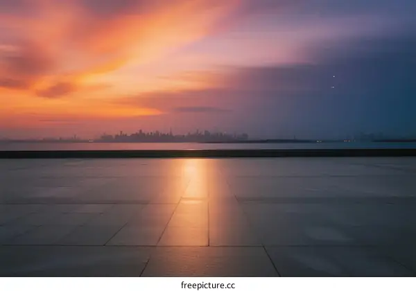 Beautiful sunset with city skyline reflecting on smooth ground