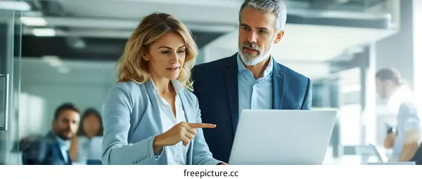 Two Business Professionals Discussing Work on Laptop in Office