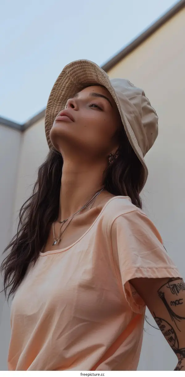 A young woman wearing a bucket hat looks up at the sky
