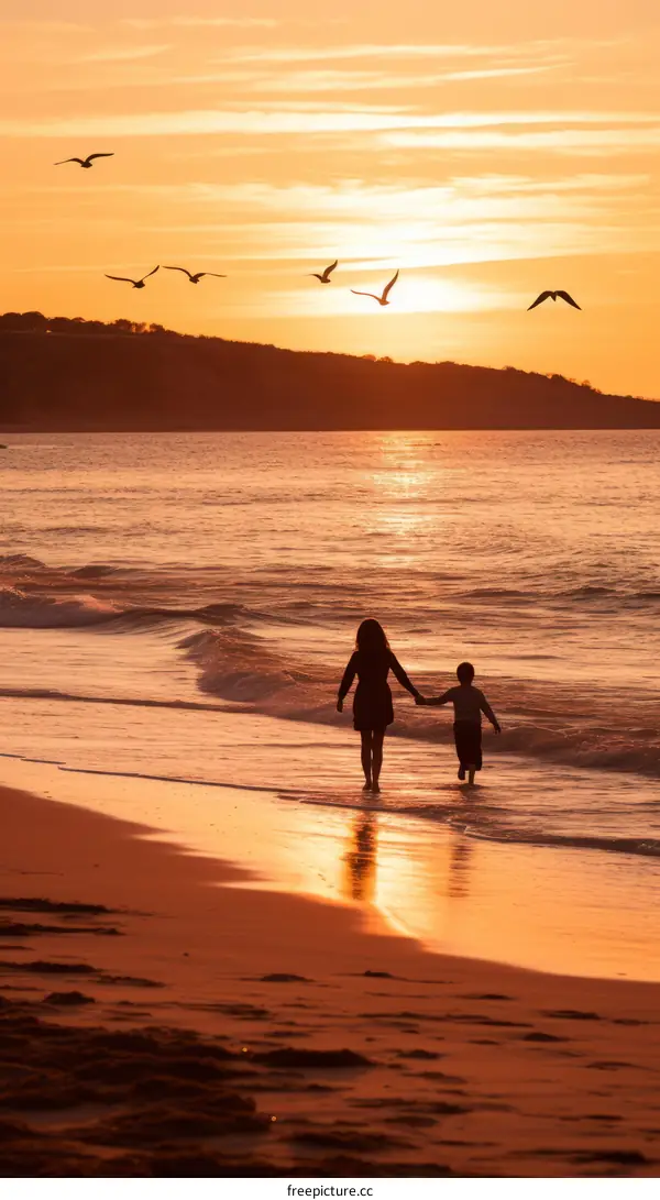 Mother and son walking on the beach at sunset