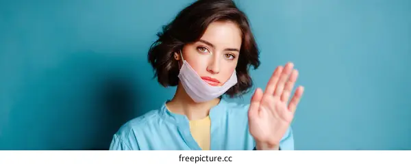 Woman Wearing Mask Showing Stop Gesture Against a Blue Background