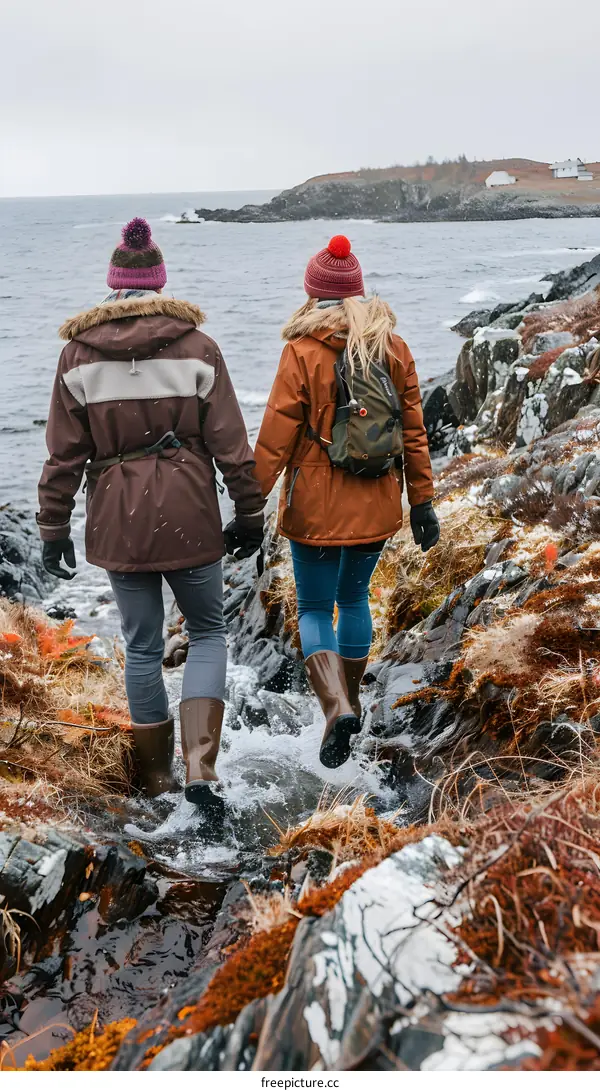 Couple Walking Through Water On Rocky Coastline In Winter