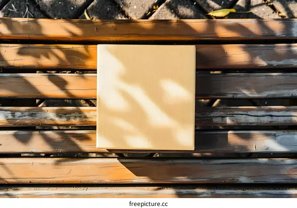 Brown Book on Wooden Bench with Sun Shadows
