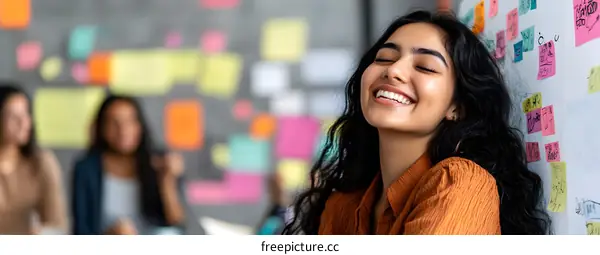 Smiling Indian Woman Leaning Against Whiteboard With Colorful Sticky Notes